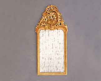 Auf dem Bild ist ein schlanker, reich geschnitzter Rokoko-Spiegel vergoldet zu sehen