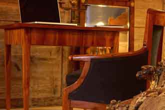 Blogartikel zum Thema Biedermeier-Möbel finden. Auf dem Bild sind verschiedene Biedermeier-Möbel zu sehen, darunter ein schlichter Tisch, ein schöner Sessel und ein Spiegel. Alles Kirschbaum-Möbel.