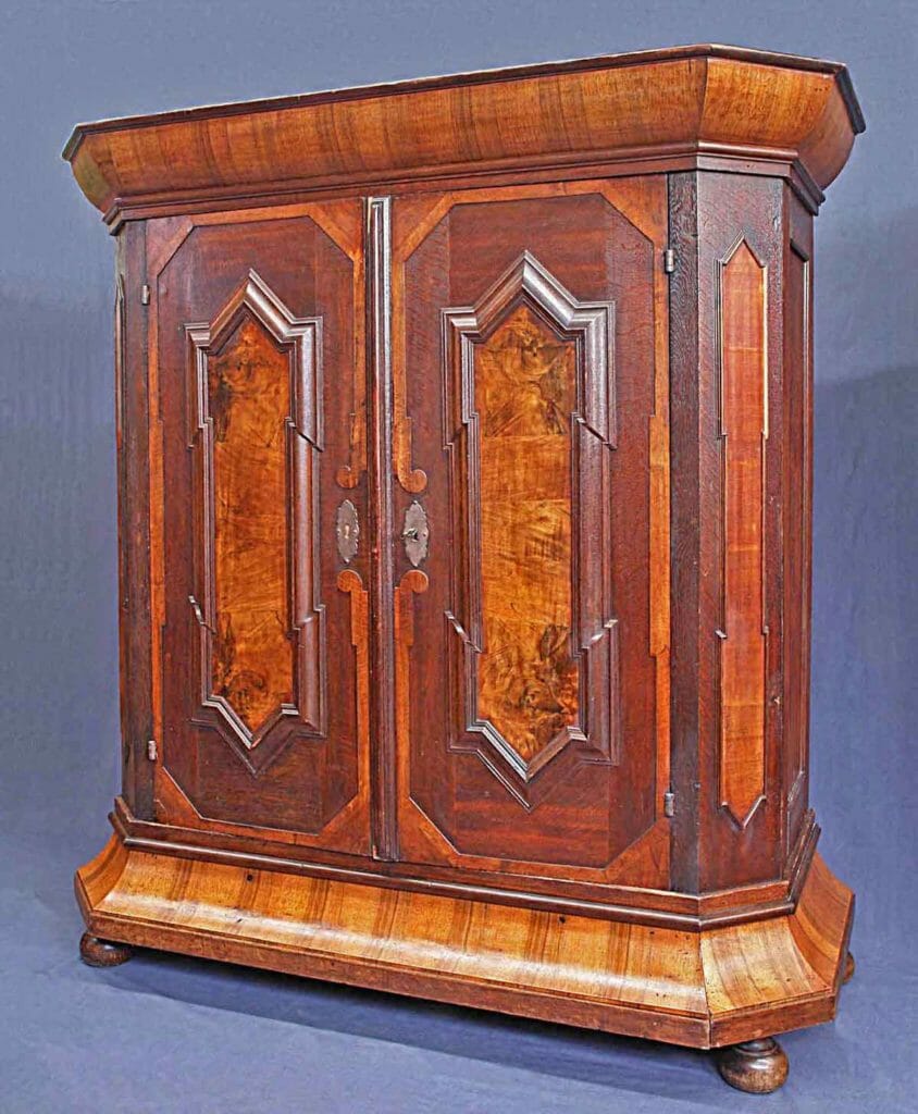 Das Bild zeigt ein Barock-Möbel nämlich einen Barockschrank süddeutsch mit Bastionsfüllungen auf den Türen und quer furnierten Profilen.
