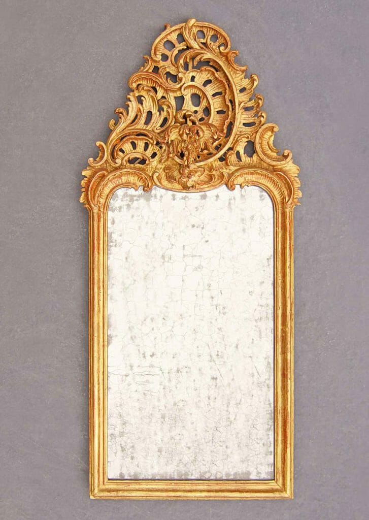 Auf dem Bild ist ein schlanker, reich geschnitzter Rokoko-Spiegel vergoldet zu sehen.