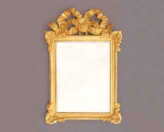 Das Bild zeigt einen vergoldeten Louis-seize-Spiegel um 1780. Er hat eine großzügige geschnitzte Schleife als Bekrönung. Klassizismus