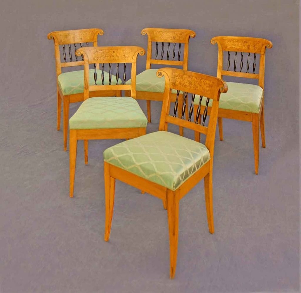 Auf dem Bild sind fünf gleiche Stühle zu sehen. Es sind Biedermeier-Möbel gebaut aus hellem Apfelbaumholz. Sie haben einen grünen Seidenbezug. Sie waren einst in Herzoglich Württembergischem Besitz.