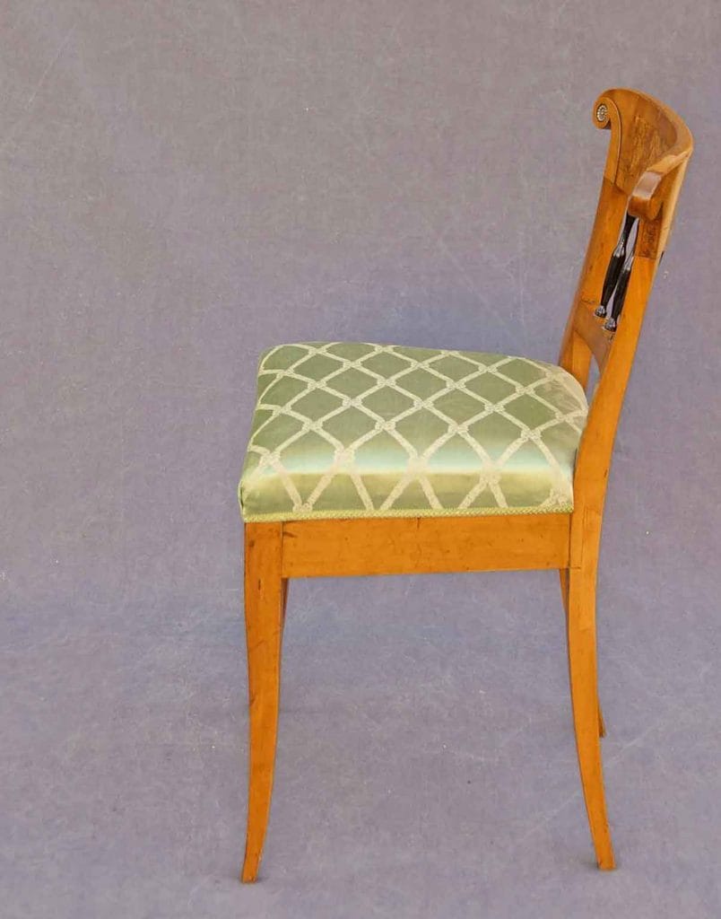Auf dem Bild ist ein Biedermeier-Möbel zu sehen. Es ist ein Stuhl mit grünem Bezug und er ist aus Apfelbaum gefertigt. Die Ansicht zeigt den Stuhl von der Seite.