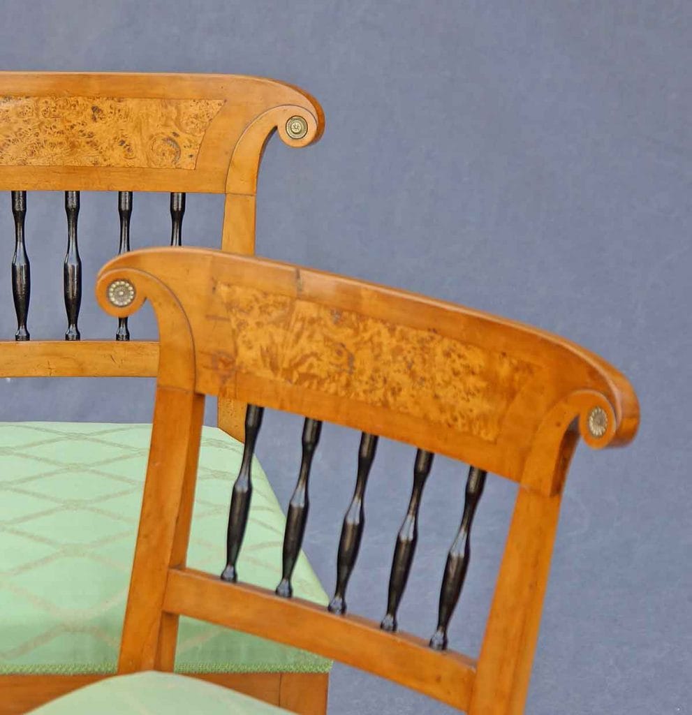 Blick auf die Lehnen des Biedermeier-Stuhlsatzes mit den schwarzen gedrechselten Balustern, den Rosetten in den Lehnenenden und dem Birke-Maserfurnier im Lehnbrett.