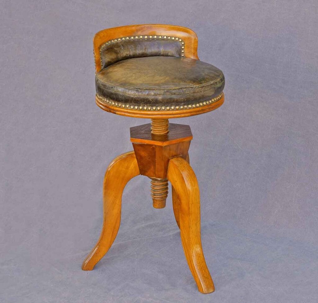 Biedermeier-Drehhocker3 Antiker Biedermeier-Drehhocker aus Kirschbaum- und Buchenholz mit Lederpolsterung, Ziernägeln und drei geschwungenen Beinen.