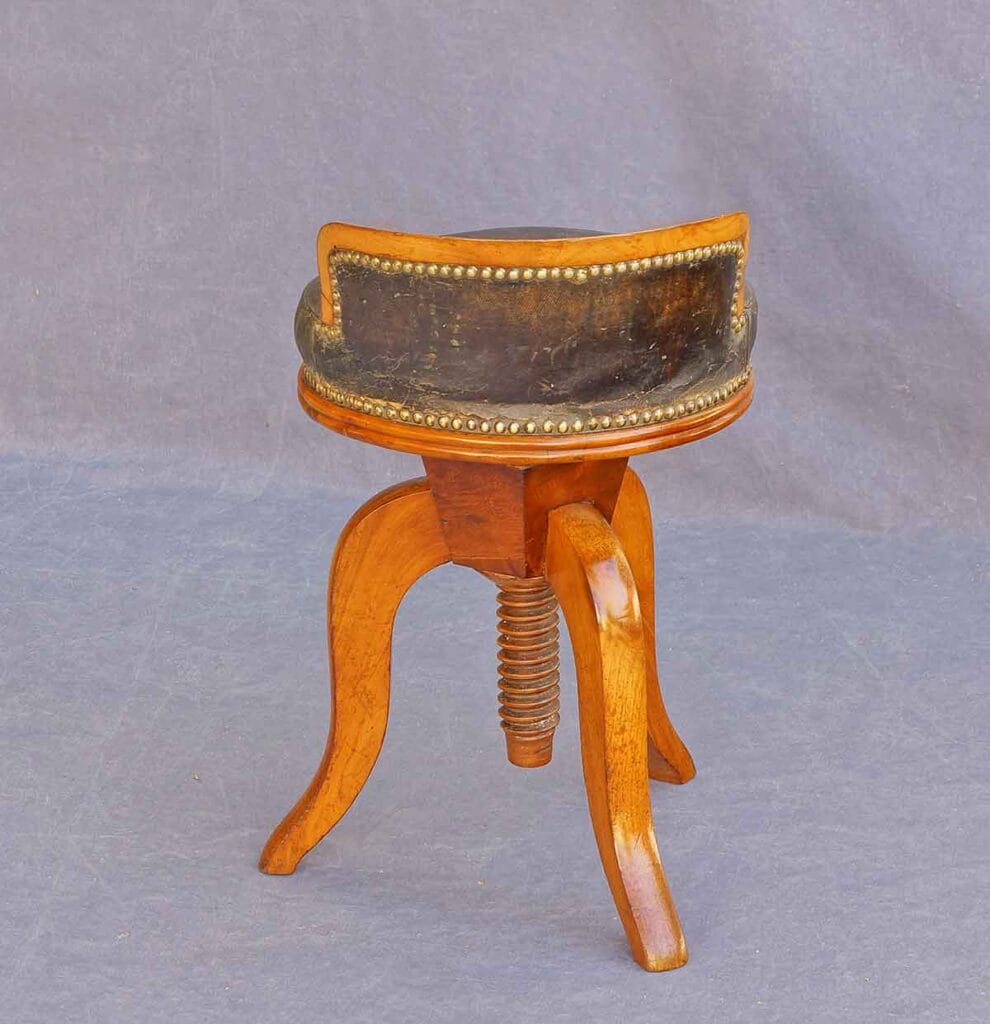 Biedermeier-Klavierhocker1 Eine Rückansicht zeigt den antiken Biedermeier-Drehhocker vor einem neutralen, grauen Hintergrund.