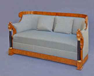 Gesamtansicht eines Biedermeier-Sofas aus Nussbaumholz mit schwarz-goldenen Säulen, hellblauem Musterstoff und zwei Kissen.